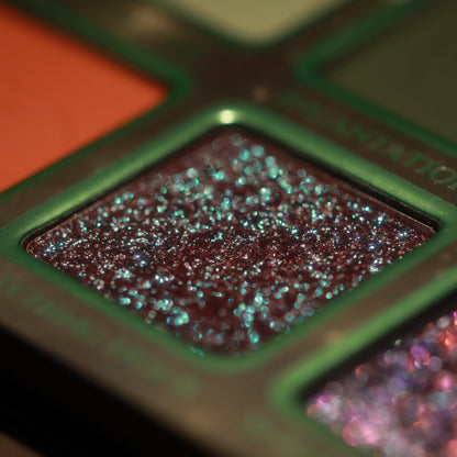 Macro of Witching Hour, a dark pan scattered with teal sparkles