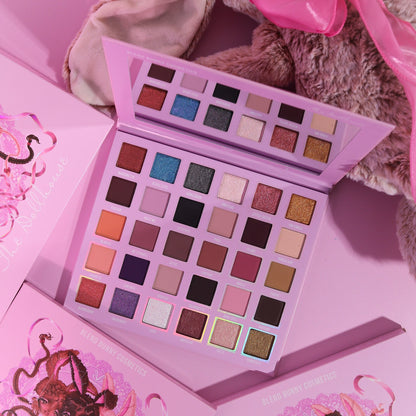 The Dollhouse magnetic palette open with its mirror, propped beside a plush bunny and closed boxes