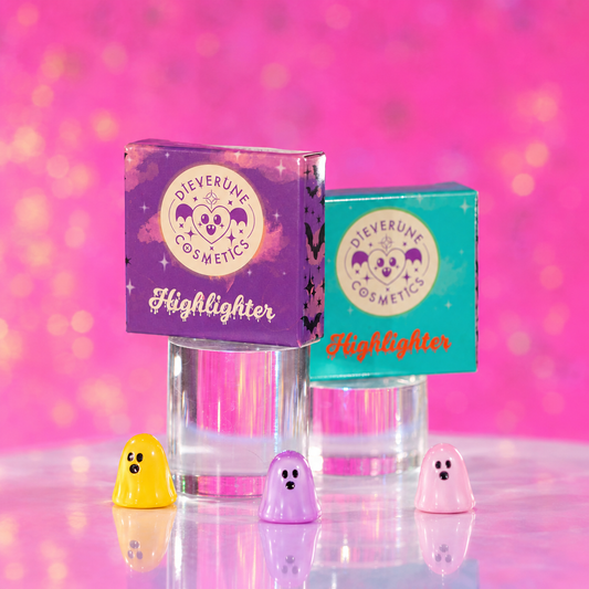 Two Dieverune Highlighter boxes, one purple and one teal, on clear stands with small ghost figures and a pink backdrop