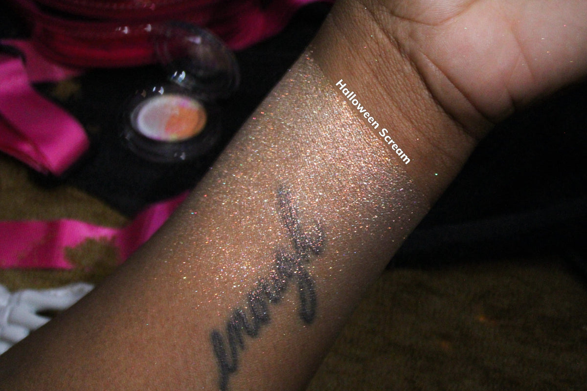 Summerween Scream swatched along a forearm on deep skin, shot on pink satin beside the compact.