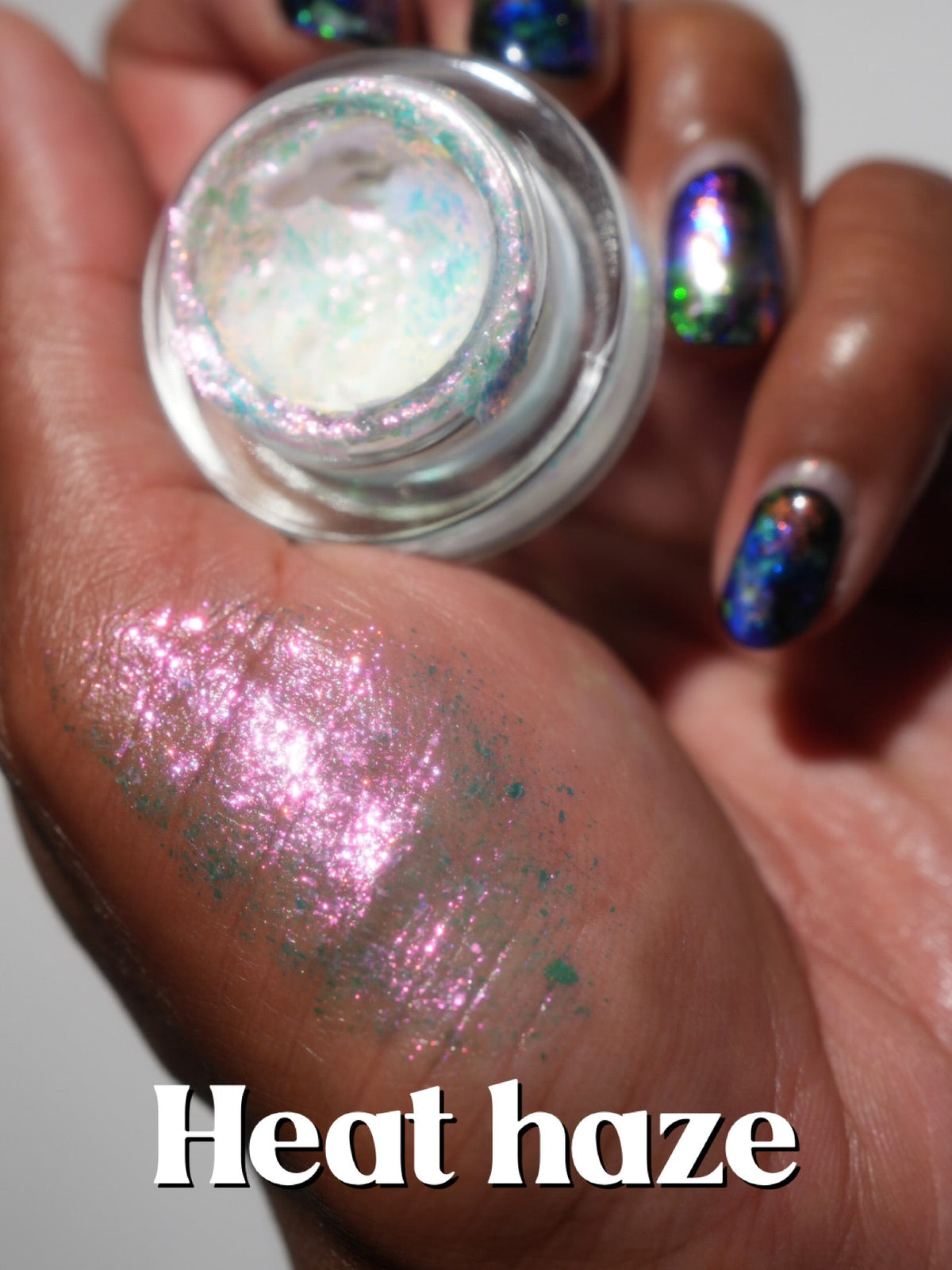 Heat Haze jar in hand with a pink finger swatch on deep skin