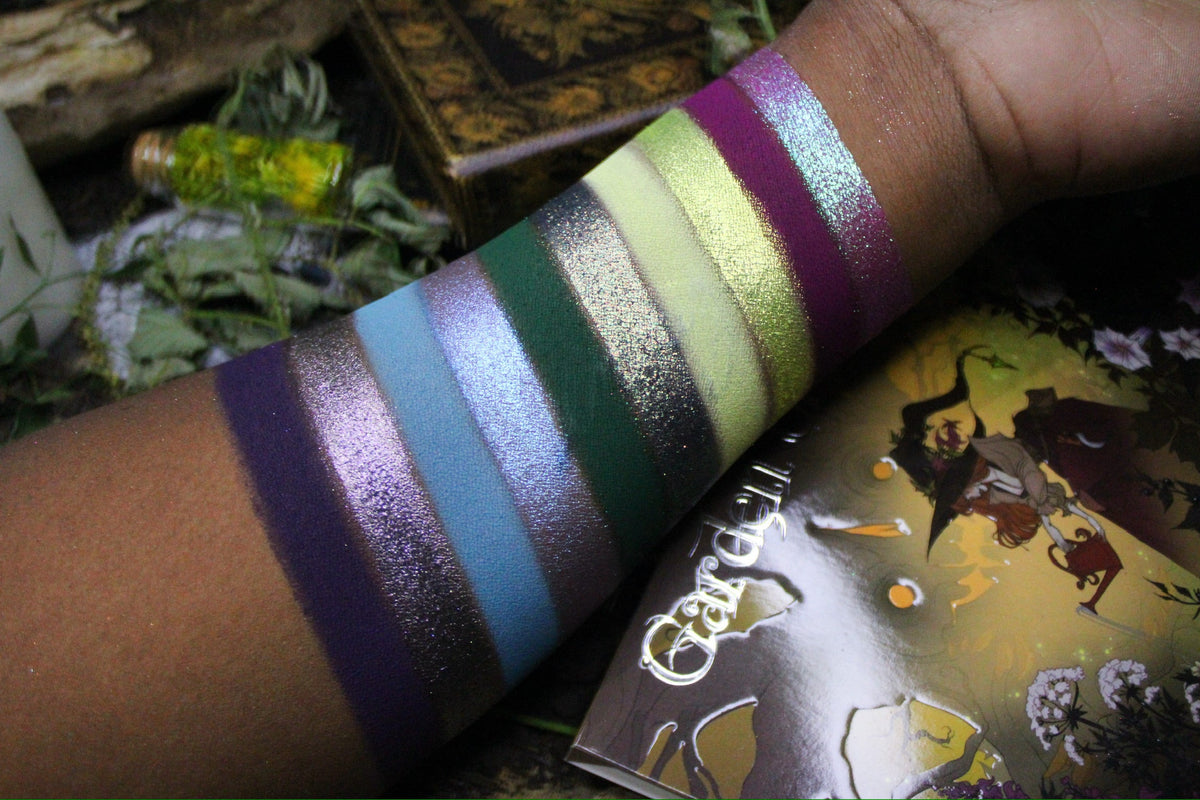 Swatches of the other ten shades on deep skin, with the palette cover in frame.