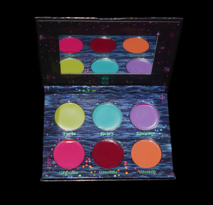 The palette open on black, the six pans reflected in the mirrored lid.