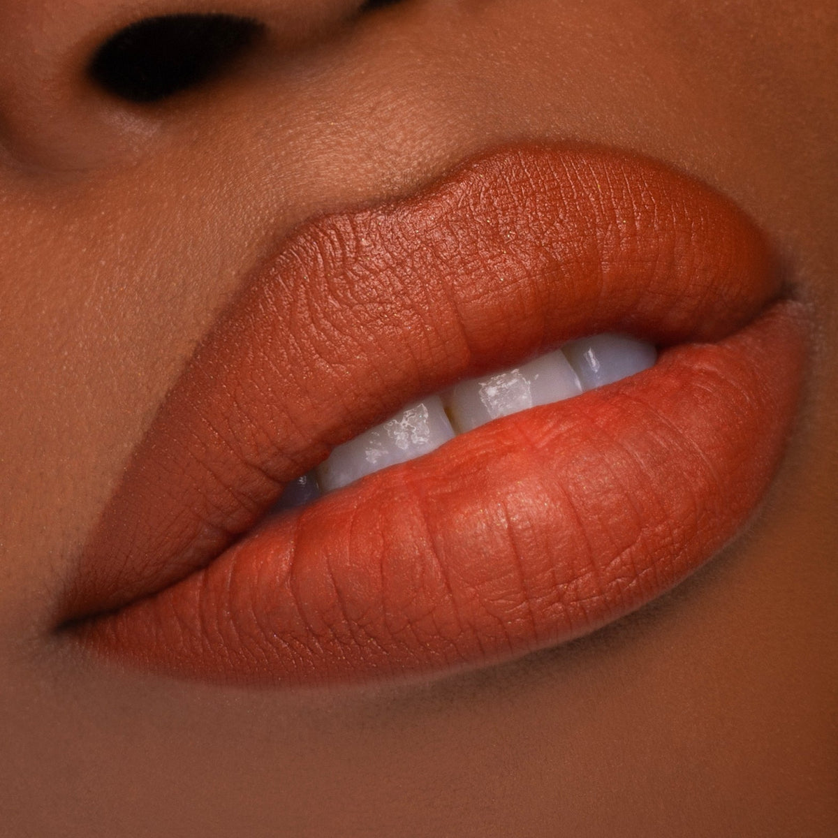Unearthly Cosmetics October Paranormal Plush lip and cheek cream worn on the lips, rusty pumpkin orange on a deep skin tone