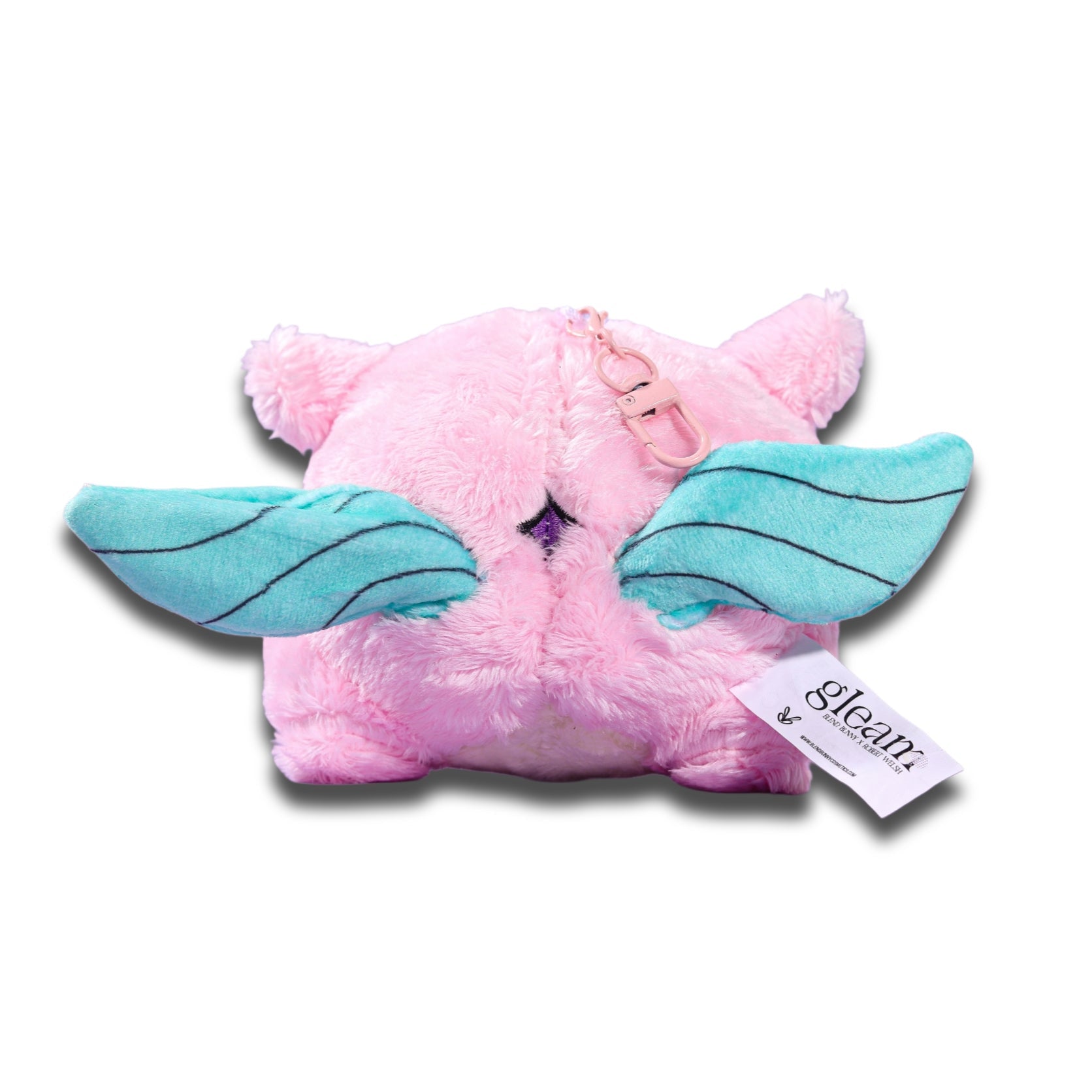 Back of the Gleam plush keychain, pink fabric with mint wings spread, the attachment loop at the top and a printed hang tag.
