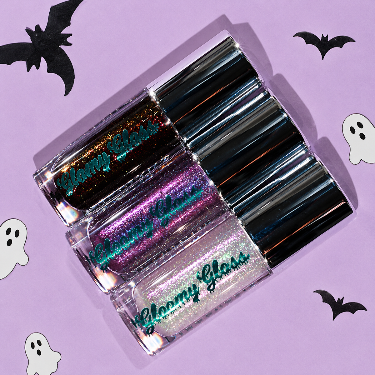 Seance Shimmer, Purple Potion and Moonlit Magic tubes lying diagonally on a lilac backdrop with black paper bats