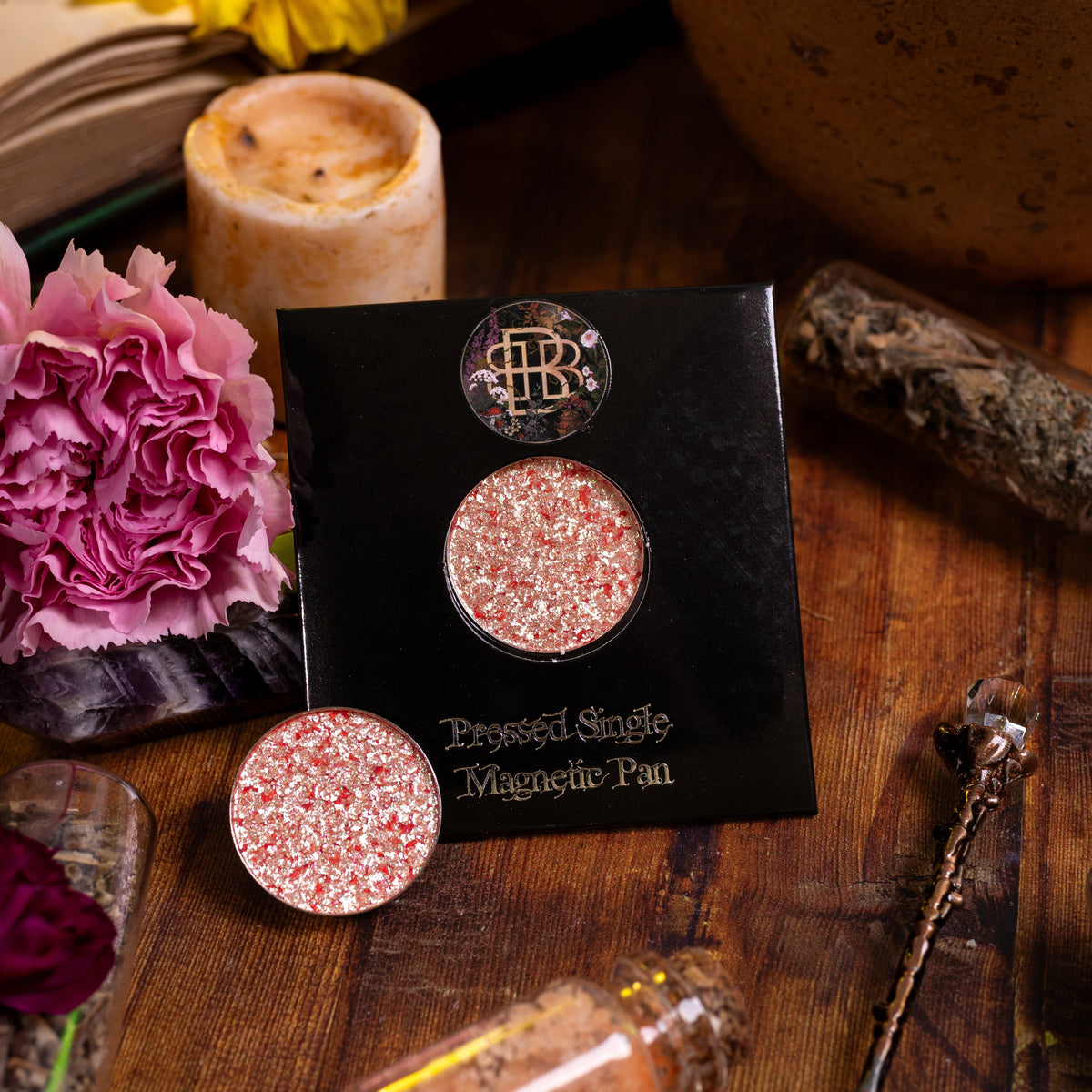 Grimoire Garden on its pressed single magnetic pan card, with a loose pan, among flowers and candles.