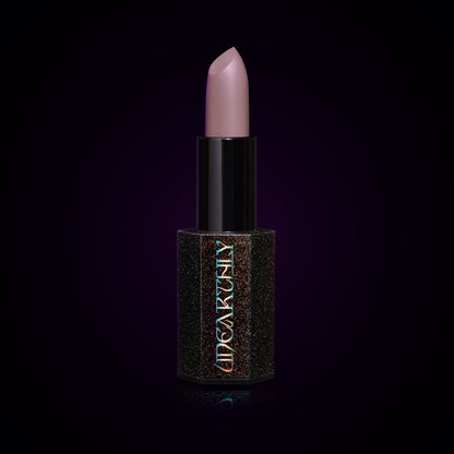 Ghost Milk lipstick bullet, pale lavender-grey cream in a black holographic-speckled tube on a dark background