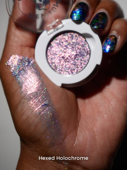 Hexed Holochrome compact in hand with a finger swatch on deep skin