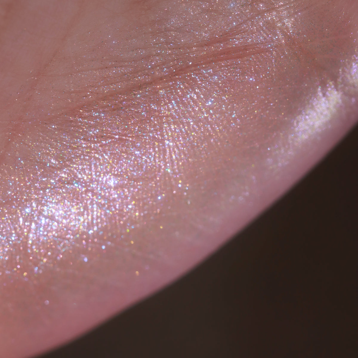 Sheer swatch close-up on light skin: pink sheen with multicoloured sparkle.