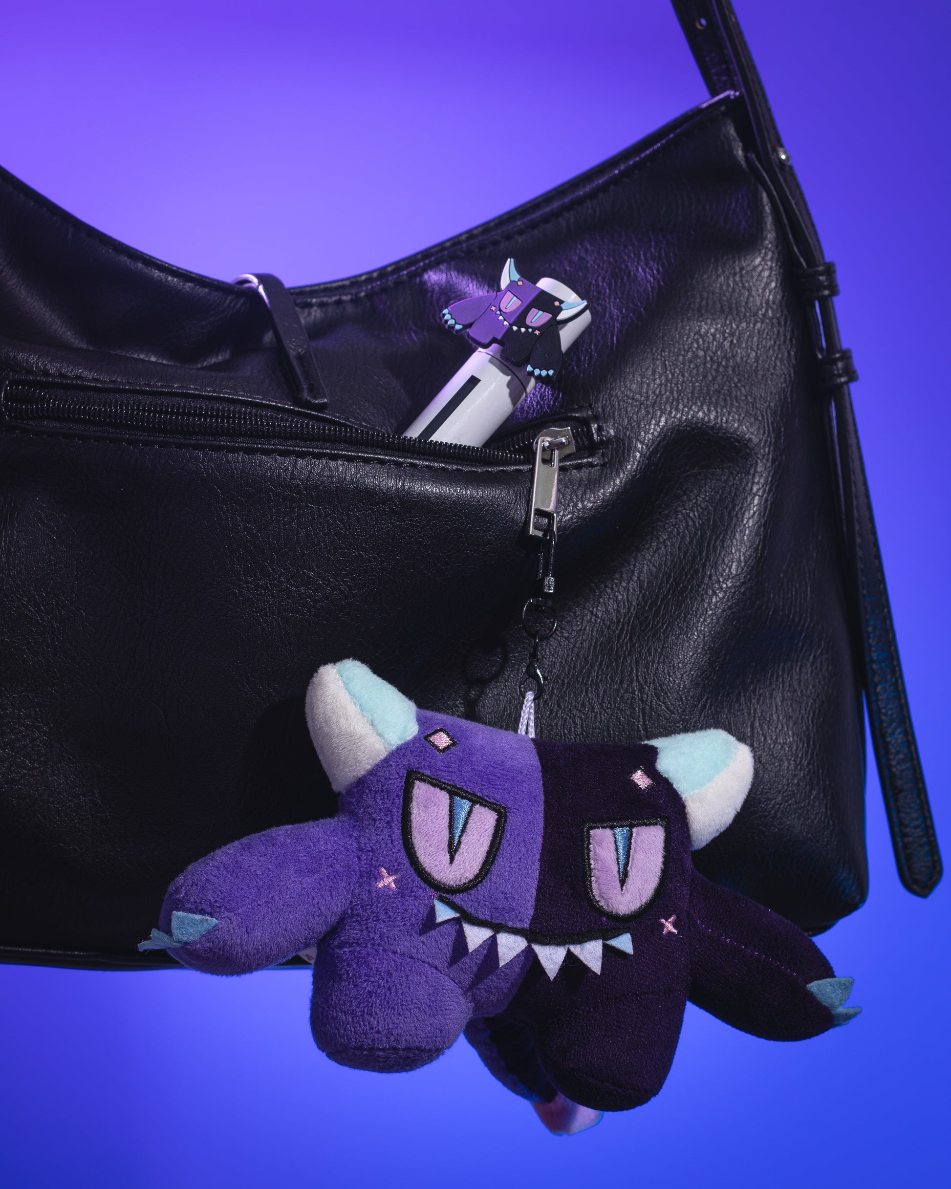 Gloom plush keychain clipped to a black leather handbag against a purple backdrop.