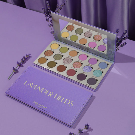 Simply Posh Lavender Fields eyeshadow palette open and closed on a lavender background, lilac faux-leather cover with gold lettering and 18 pans inside