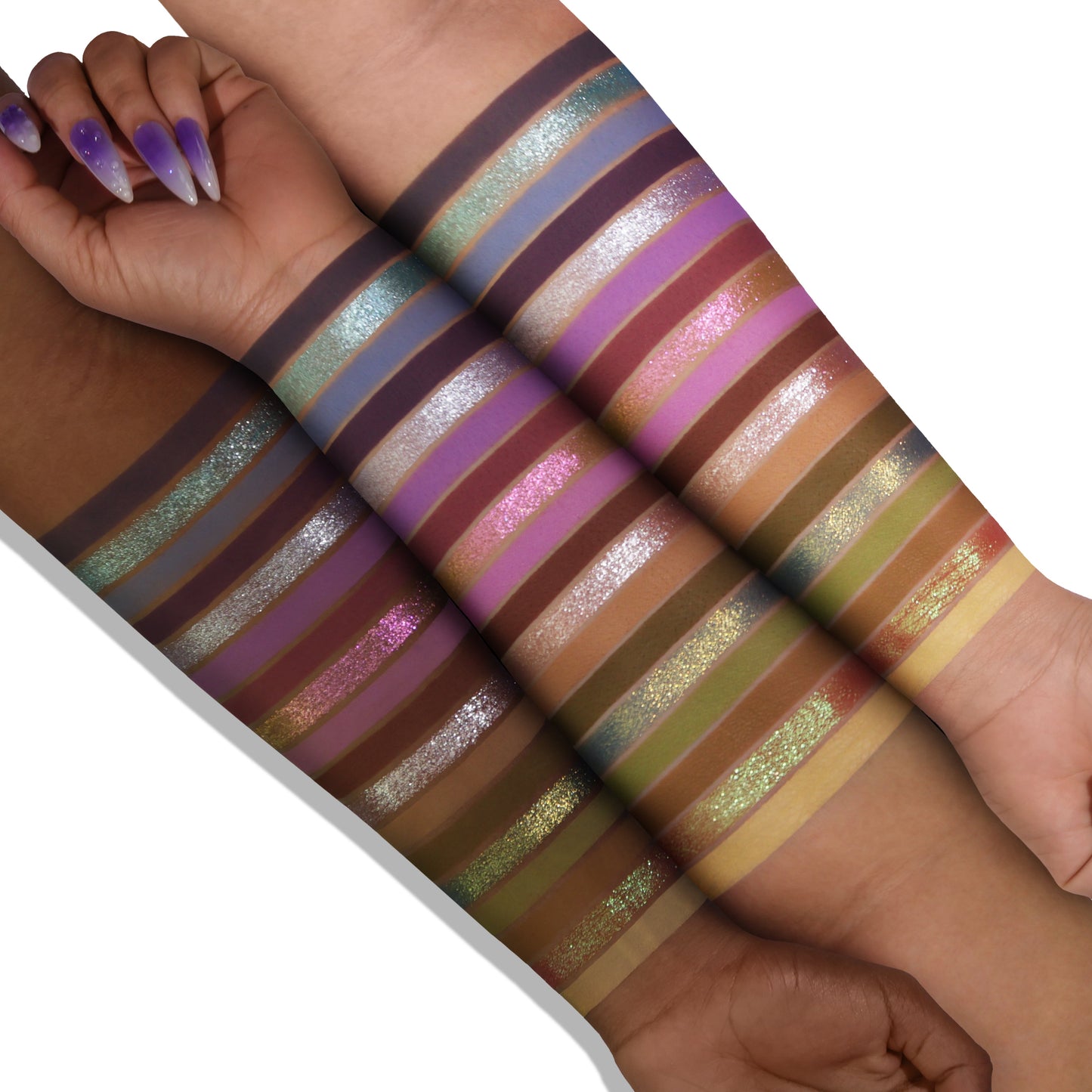 Lavender Fields palette swatches on two skin tones, 18 stripes from lilac and violet to green, gold, and silver shimmer over matte purples and neutrals