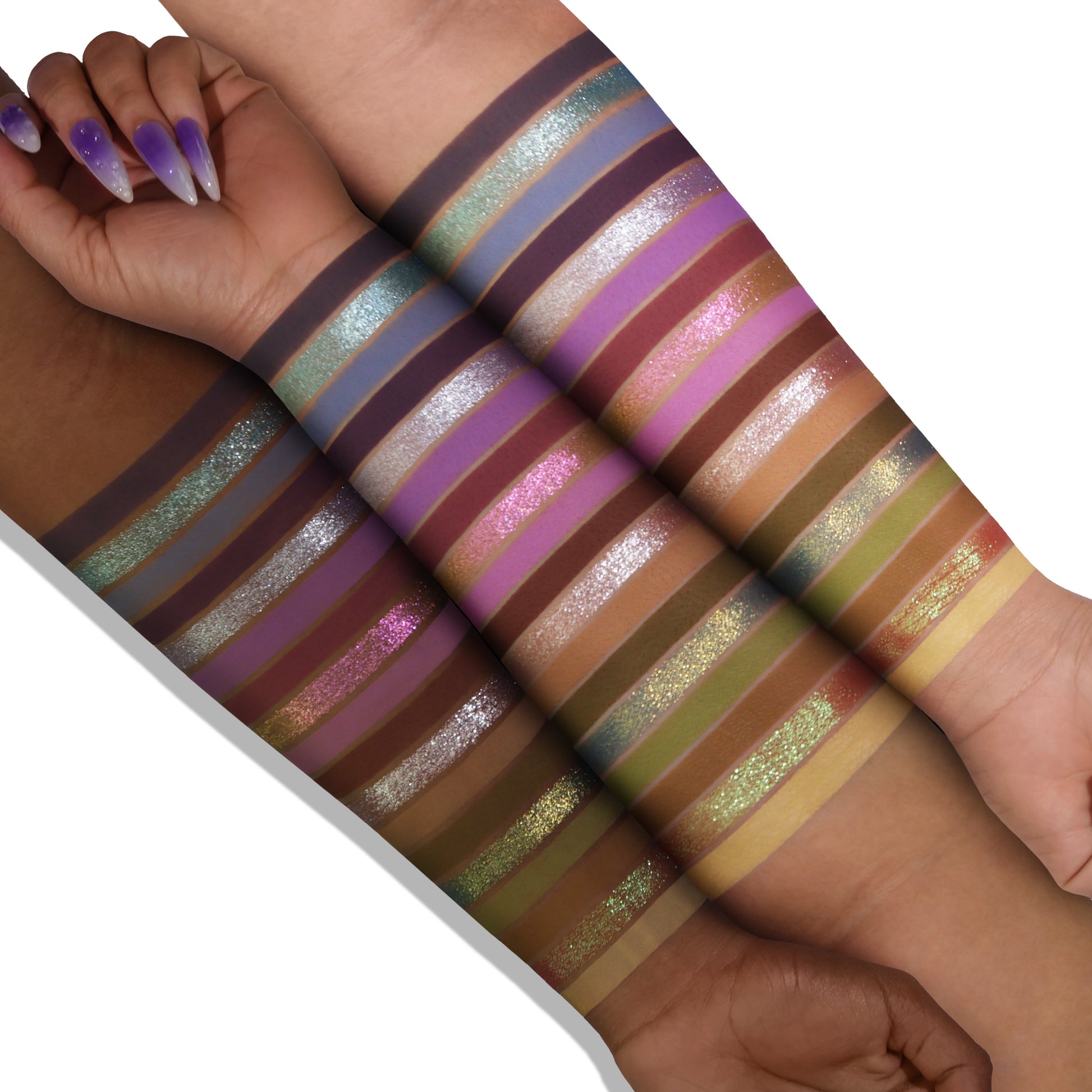 Lavender Fields palette swatches on two skin tones, 18 stripes from lilac and violet to green, gold, and silver shimmer over matte purples and neutrals