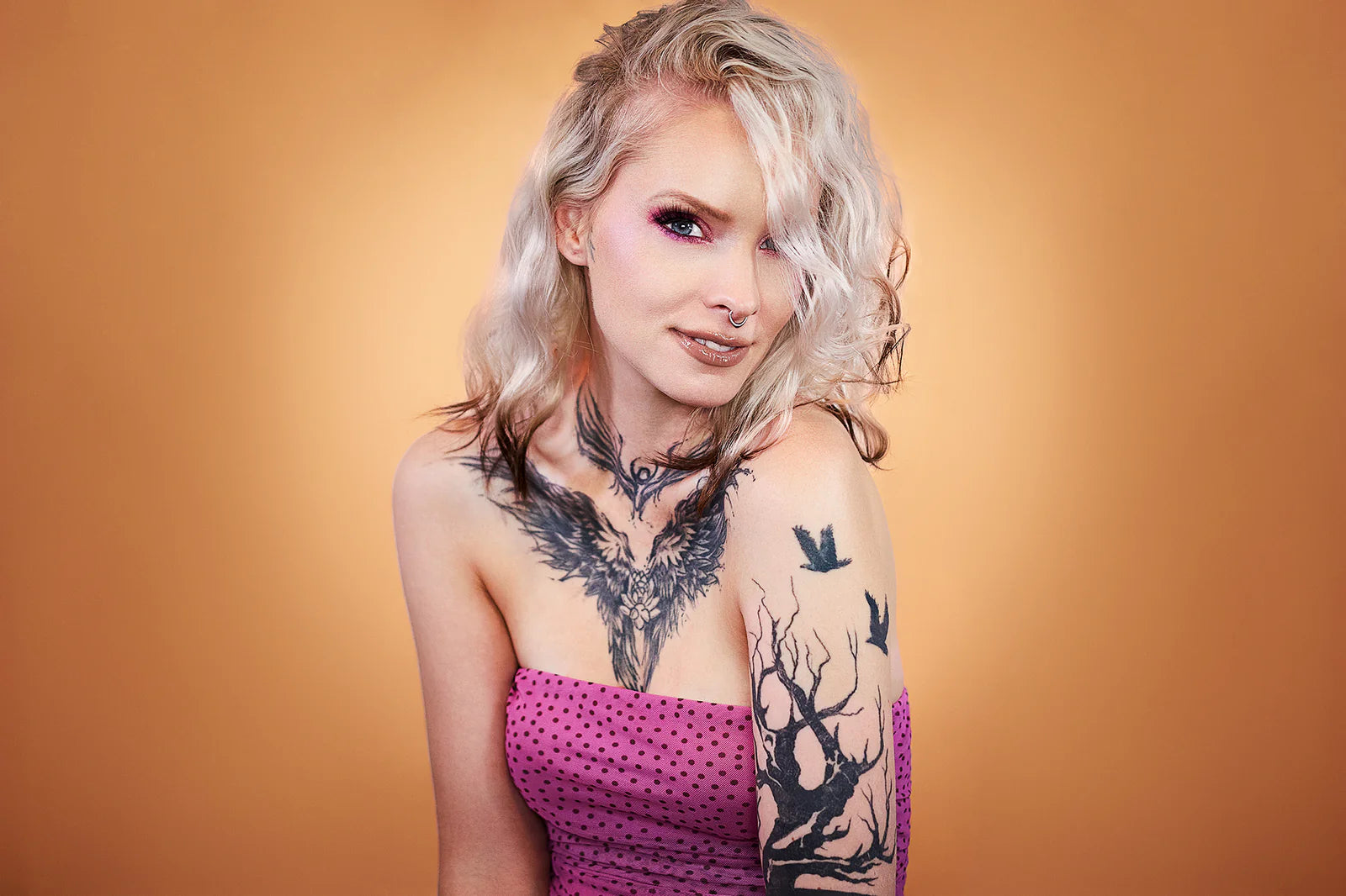 Model with pale skin and blonde waves wearing a pink and purple Succulent Dew eye look against a warm amber backdrop