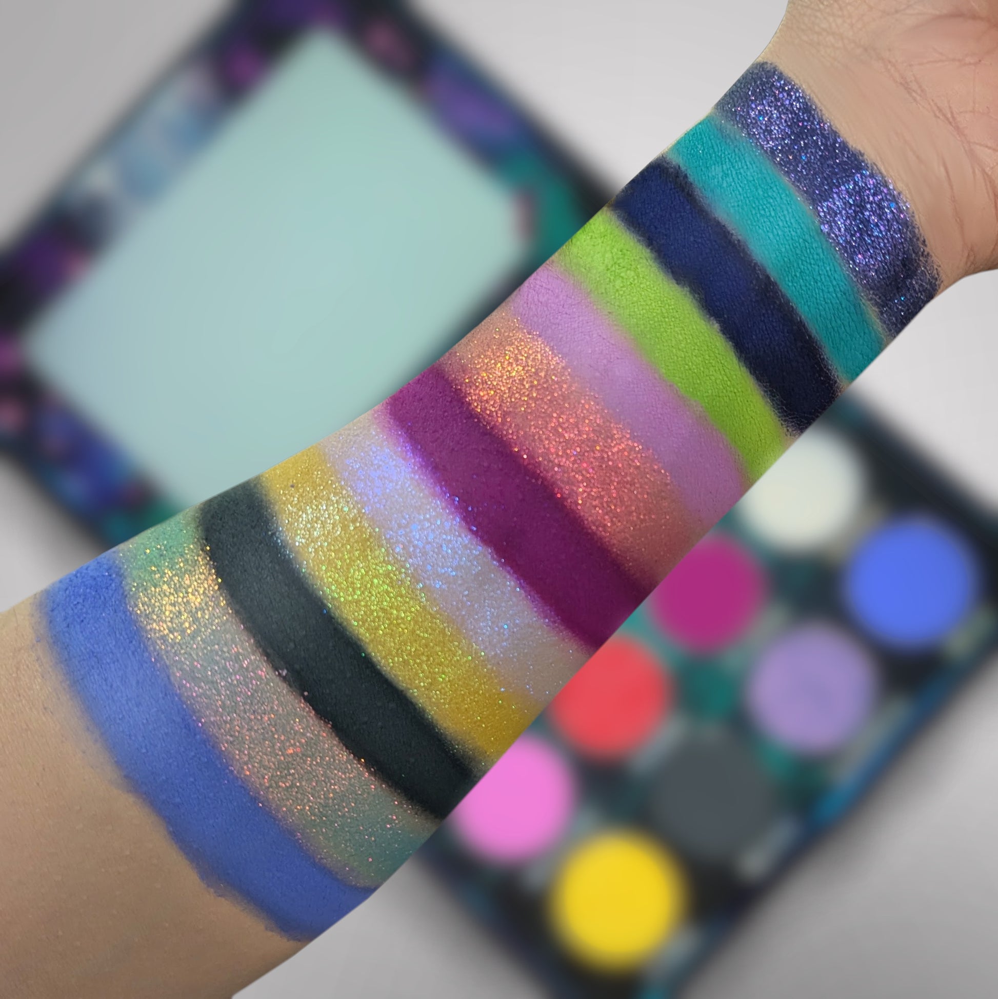 Cosmic Cove swatches on light skin tone showing all twelve shades laid out in stripes, sparkles and mattes side by side