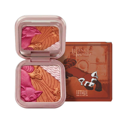 Open compact beside its box on a white background, pan embossed in pink, coppery orange and pale pearl, box illustrated with Pabu in burnt orange