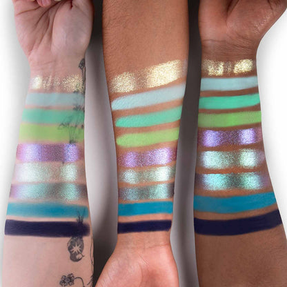 Raava palette swatched on three skin tones: greens, gold, teal, a purple duochrome, and navy across nine shades