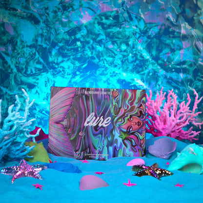 Lure palette closed, cover art of a mermaid in swirling pink, purple and green, standing on blue sand between pink and white coral