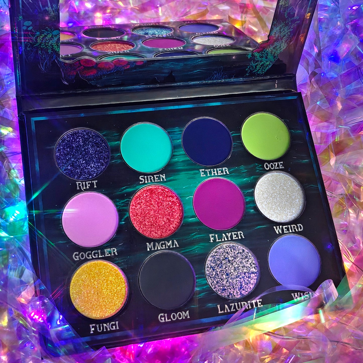 Cosmic Cove palette open at an angle on an iridescent backdrop, mirror reflecting the top row with Rift, Siren, Ether, and Ooze visible