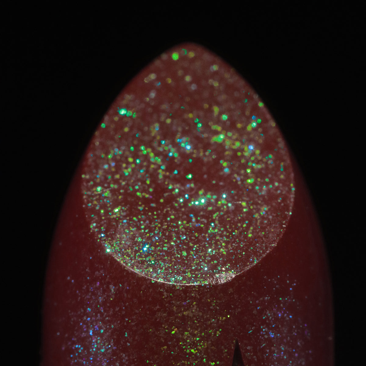 Macro of the bullet tip, red-brown with green, blue and gold sparkle.