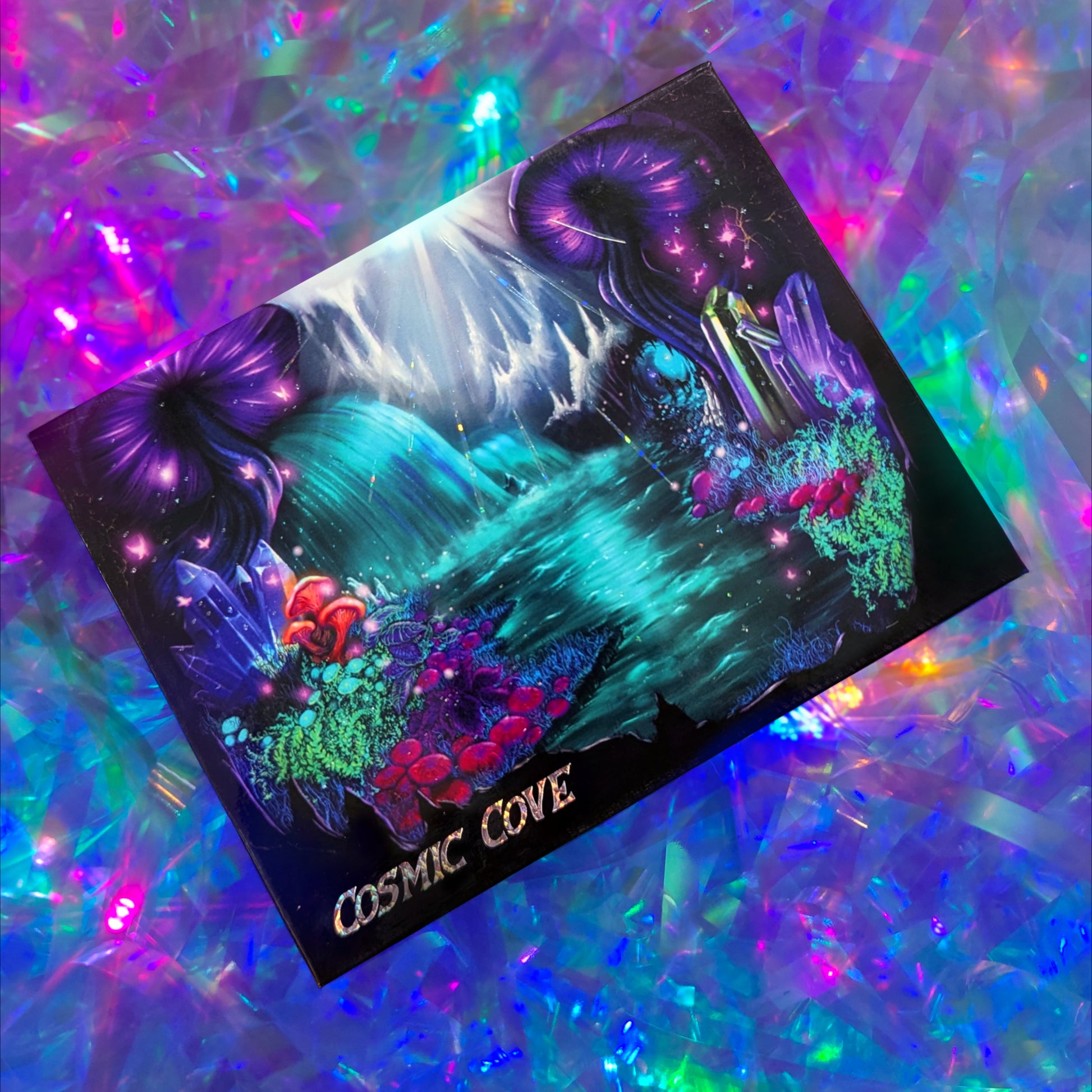 Cosmic Cove closed palette on a holographic backdrop, cover art shows purple jellyfish, teal waterfall, mushrooms, crystals, and the Cosmic Cove title