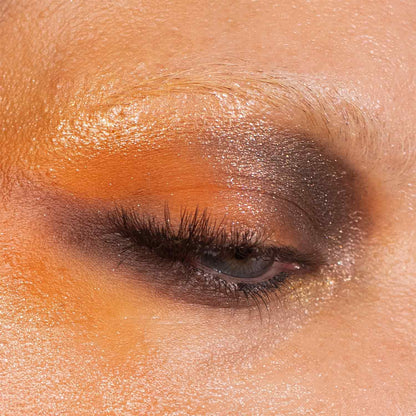 Close-up of a warm orange and brown eye look with a gold sparkle lid