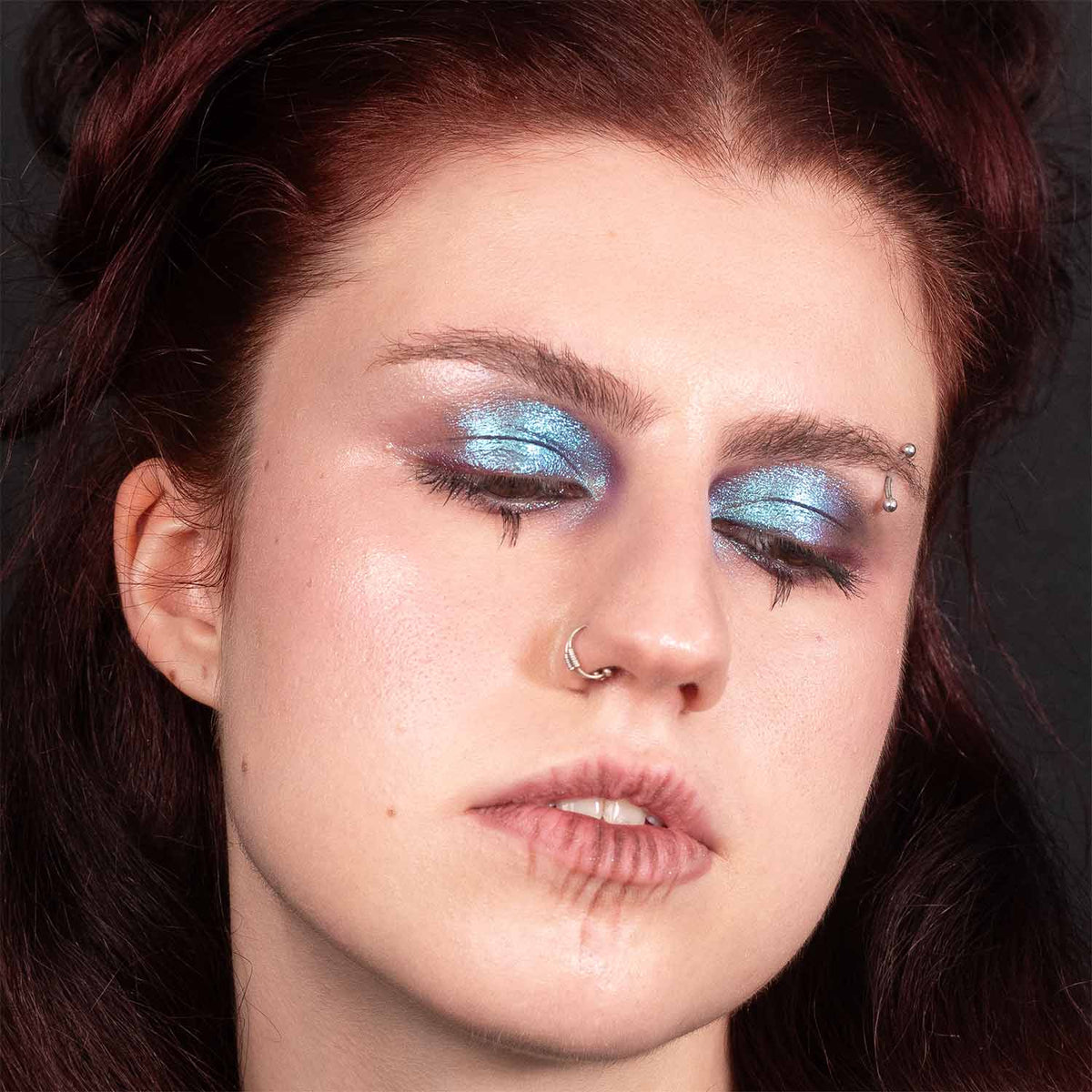 Close-up of a metallic blue eye look with plum accents