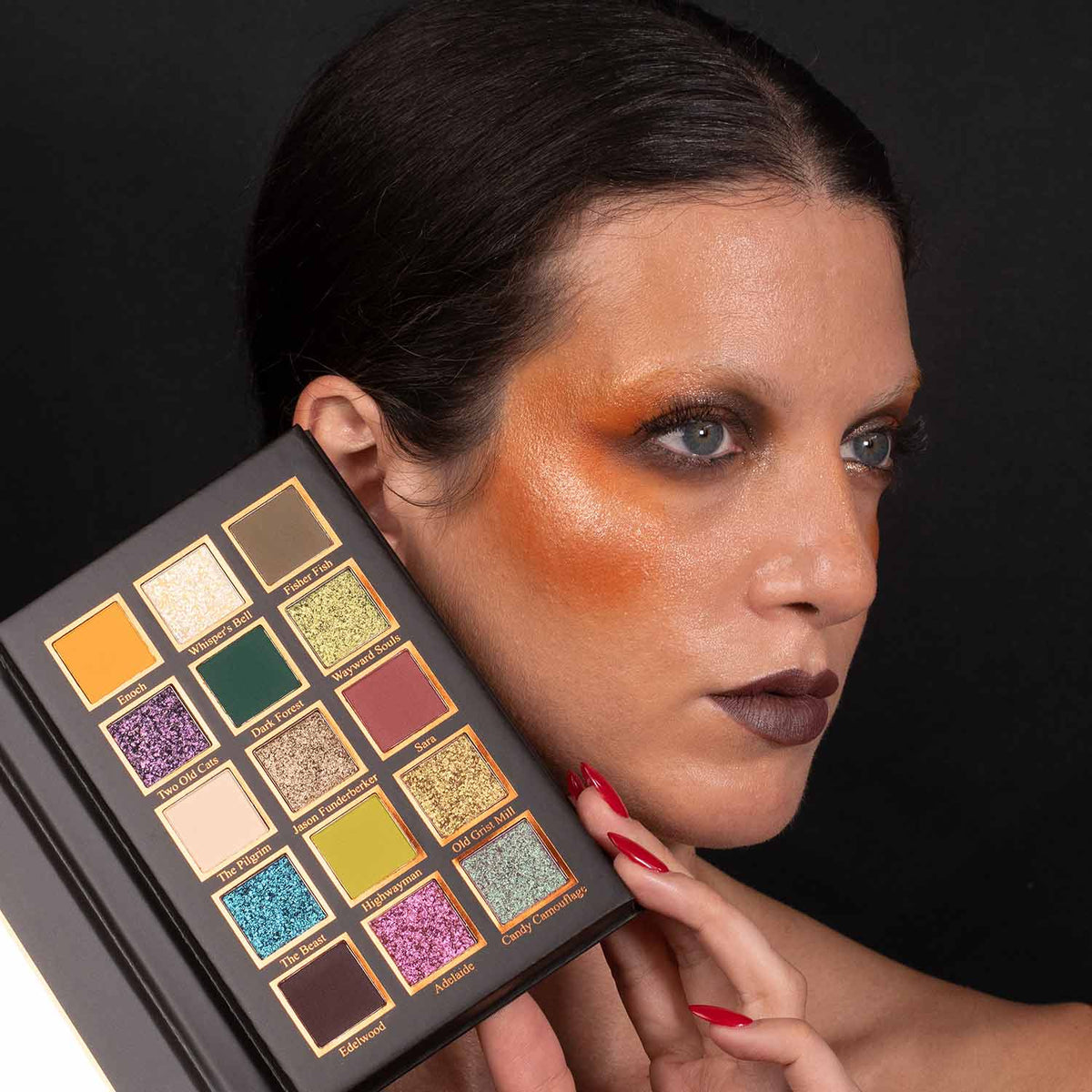 Model holding the open palette beside her face, wearing an orange and brown eye look