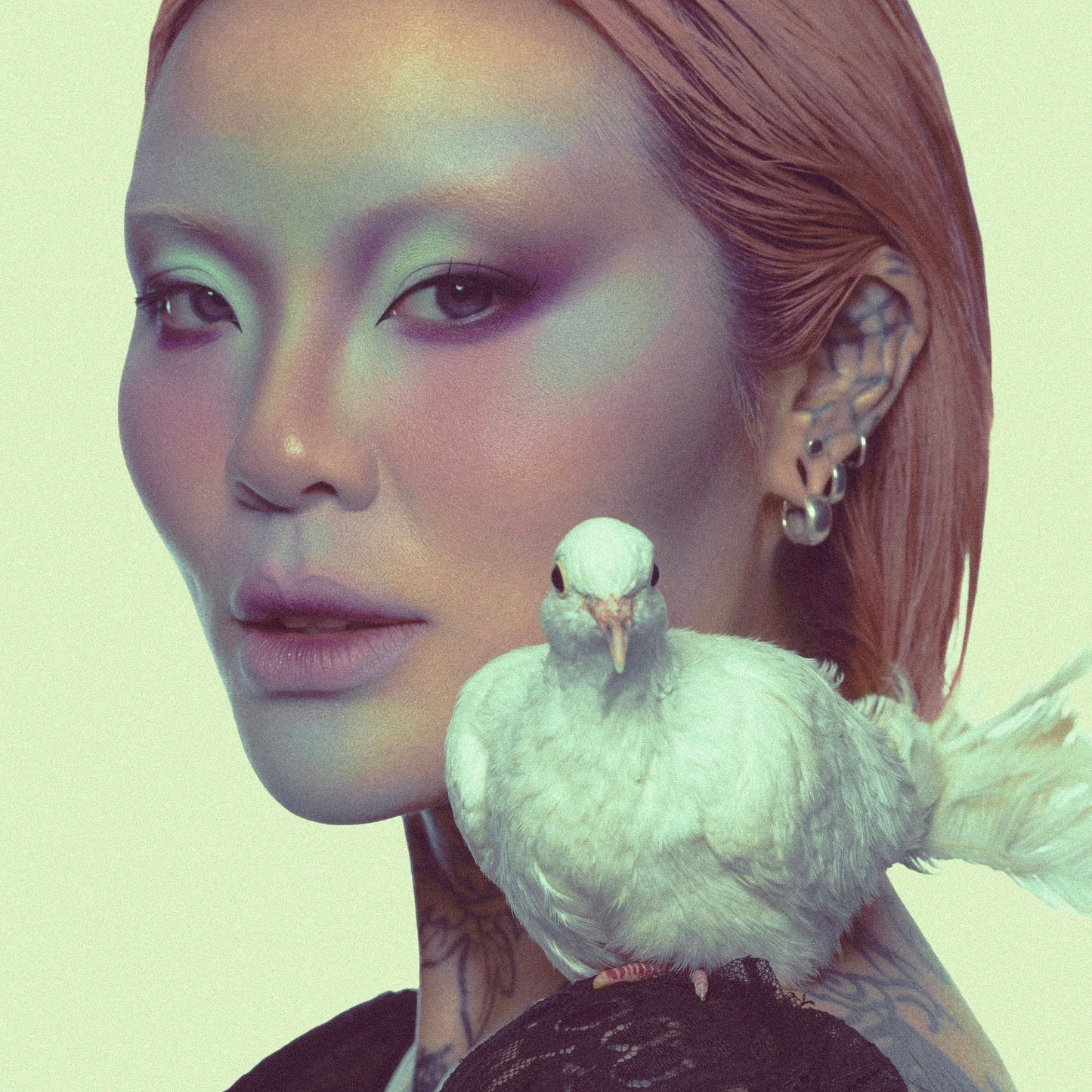 Model in a green-toned Fauna campaign look with a white dove resting on her shoulder