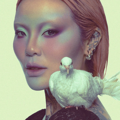 Model in a green-toned Fauna campaign look with a white dove resting on her shoulder