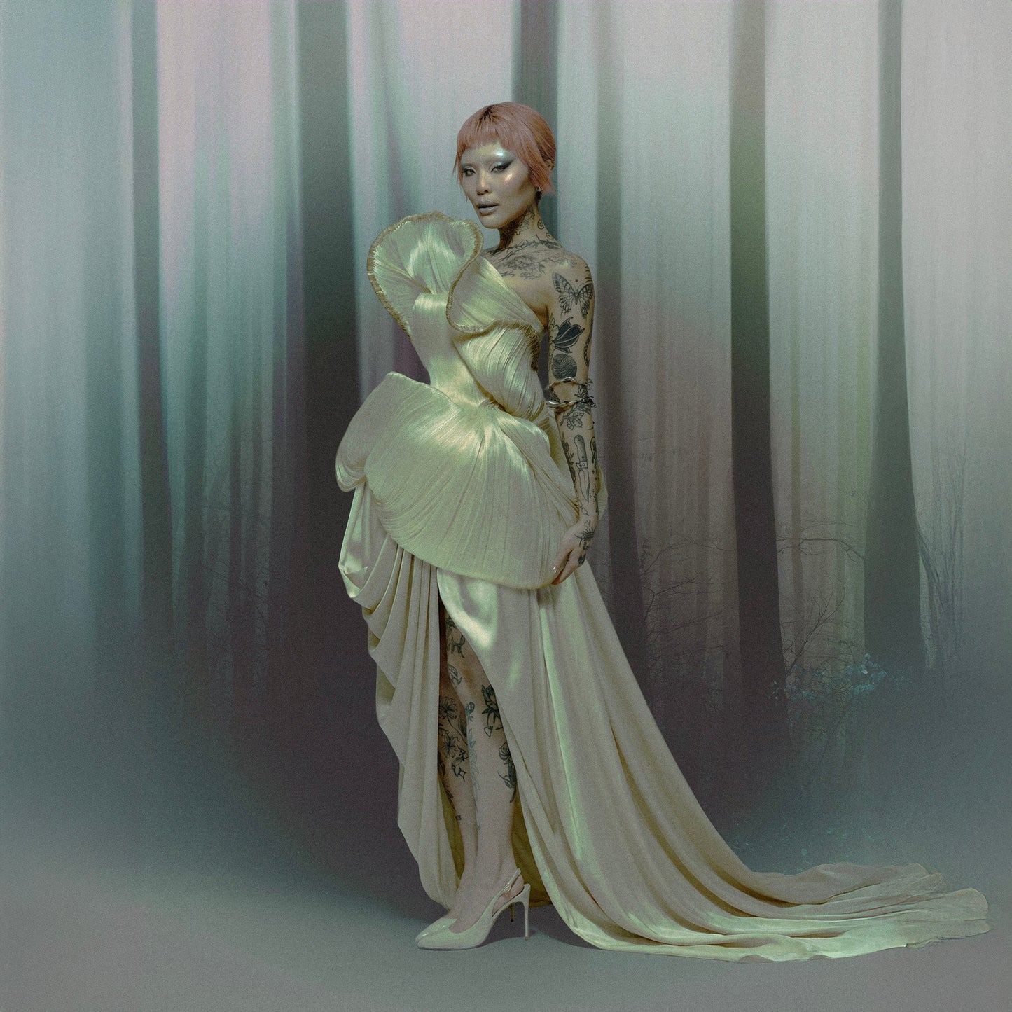 Model in a sage green gown in a misty forest, styled for the Flora campaign