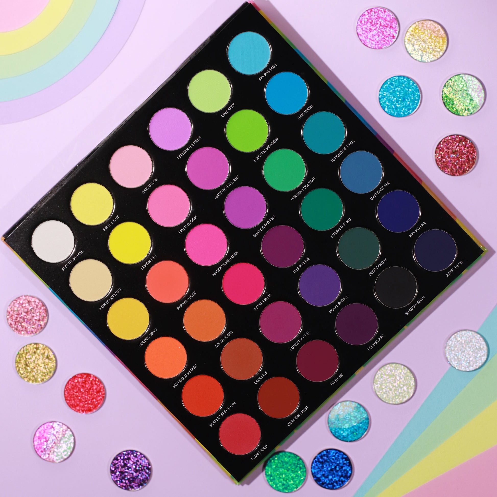 Arch of Color palette open and flat, 36 round matte pans in six rainbow rows, with matching pressed sparkle singles on a pastel rainbow background