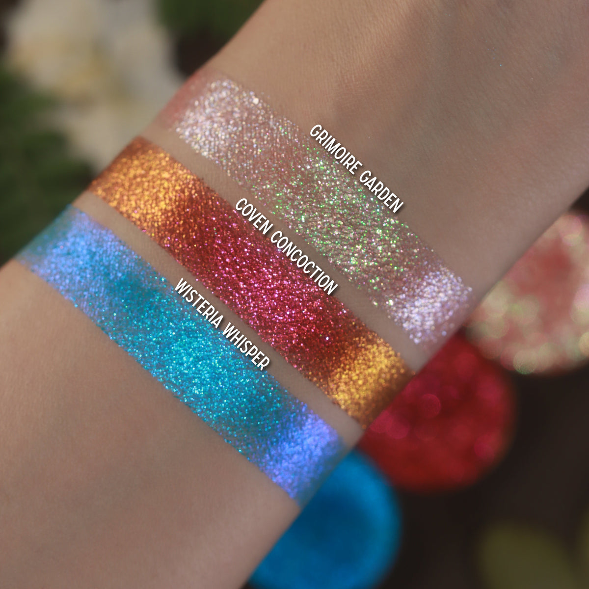 Labelled swatches of all three singles on light skin, with the pans behind.