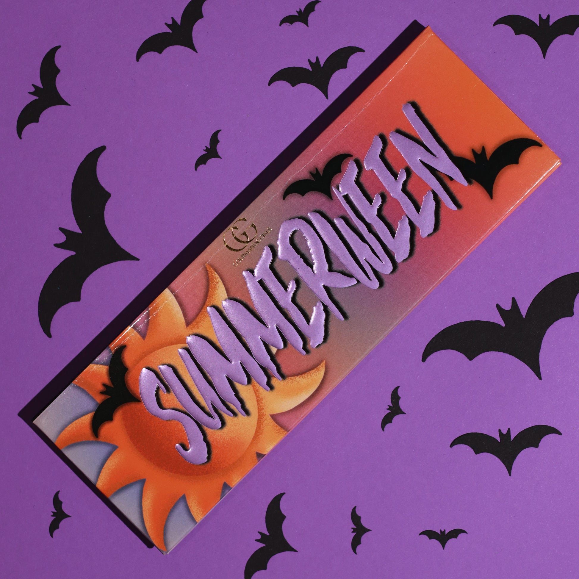 Closed Summerween palette with an orange sunset lid, purple SUMMERWEEN lettering, a sun and bats, on a purple bat-print background