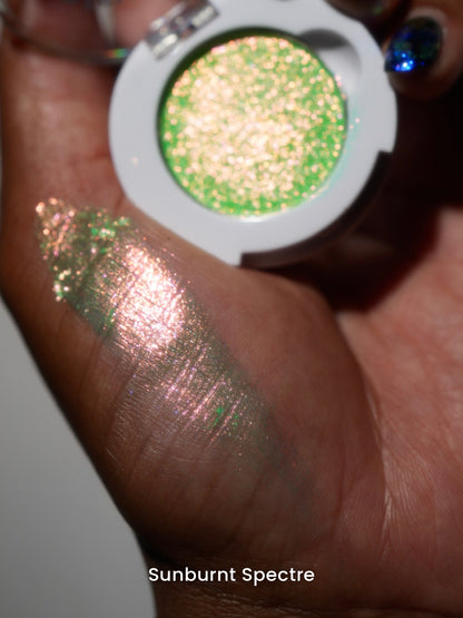 Sunburnt Spectre compact in hand with a finger swatch on deep skin