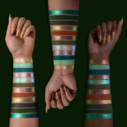Terra Moons Cosmetics Ophiuchus palette swatches on three skin tones - teal glitter, forest green, dark olive, bronze duochrome, terracotta, pink shift, and mint shades