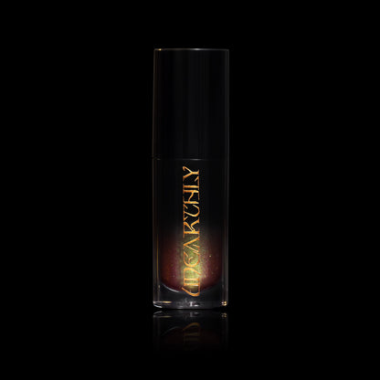 Witches Brew in a clear tube with a black cap and gold Unearthly logo, rusty gloss with a green shift showing through
