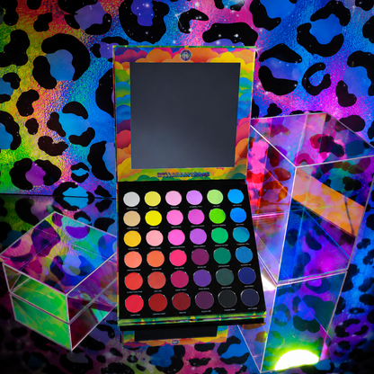 Bellabeautebar Arch of Color eyeshadow palette open upright, mirror in lid, 36 round matte pans in rainbow rows on a neon leopard print backdrop
