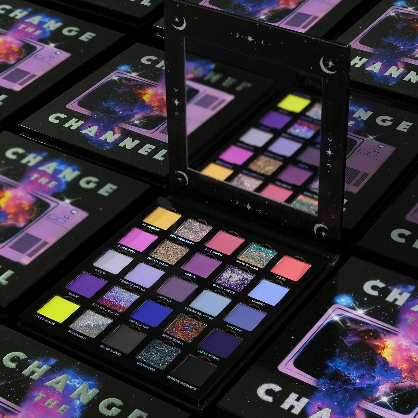 Several closed Change the Channel boxes with cosmic television cover art around one open palette and its mirror