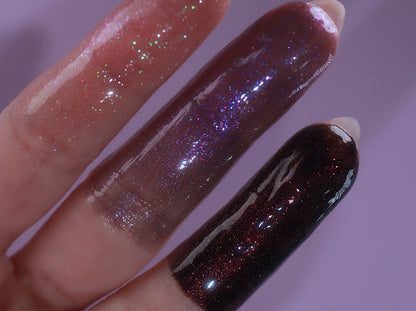 Finger swatches of the three glosses, clear with sparkle, sheer purple, and black with red sparkle