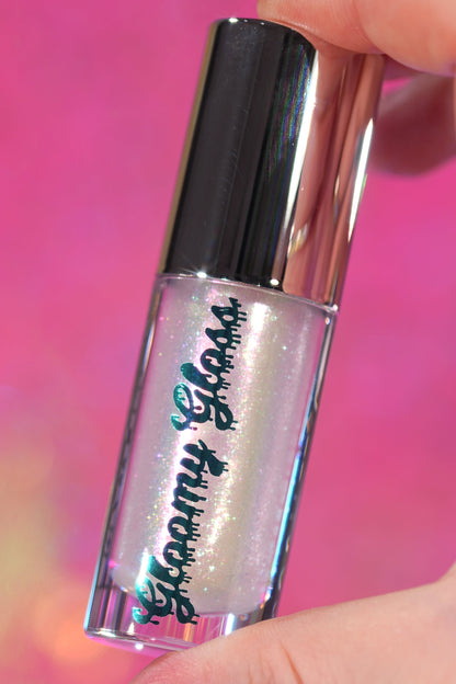Moonlit Magic tube held against a pink backdrop, a clear base with pink and green iridescence