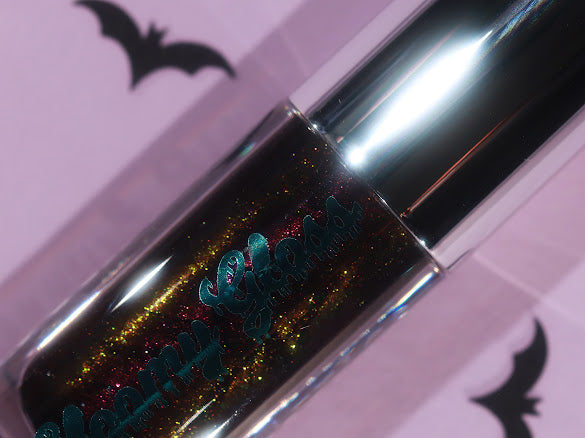 Seance Shimmer tube on a lilac backdrop with paper bats, gold and red sparkle in a black base