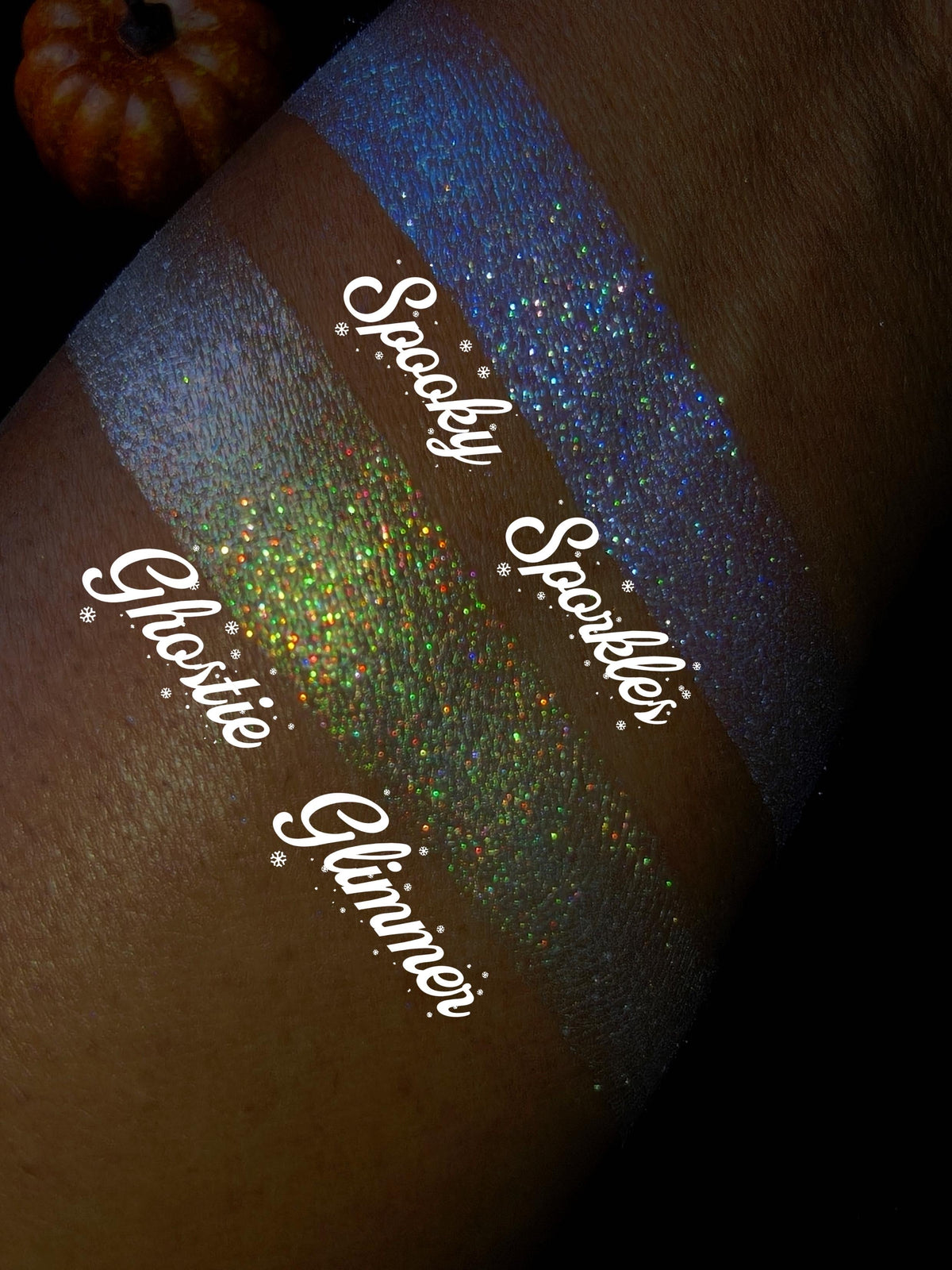 Spooky Sporkle and Ghostie Glimmer swatched side by side on deep skin, brand script labels, pumpkin in the corner