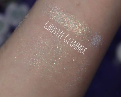 Ghostie Glimmer swatch on a fair forearm, navy background, brand label
