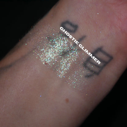 Ghostie Glimmer swatch: sparkle swatch over a tattooed wrist on a black background, brand label across it
