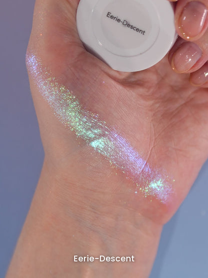 Eerie-Descent swatched on the back of a hand that holds the compact, shade name on the lid