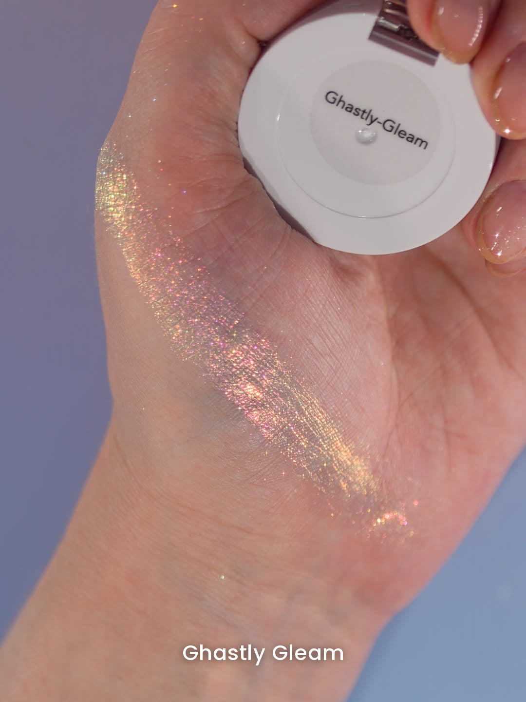 Ghastly Gleam swatched on the back of a hand that holds the compact, shade name on the lid
