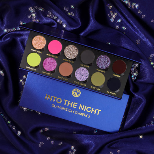 Glaminatrix Into the Night eyeshadow palette open on navy satin, 12 shades of neon pink, lime, lilac sparkles, and smoky mattes, with the closed box below
