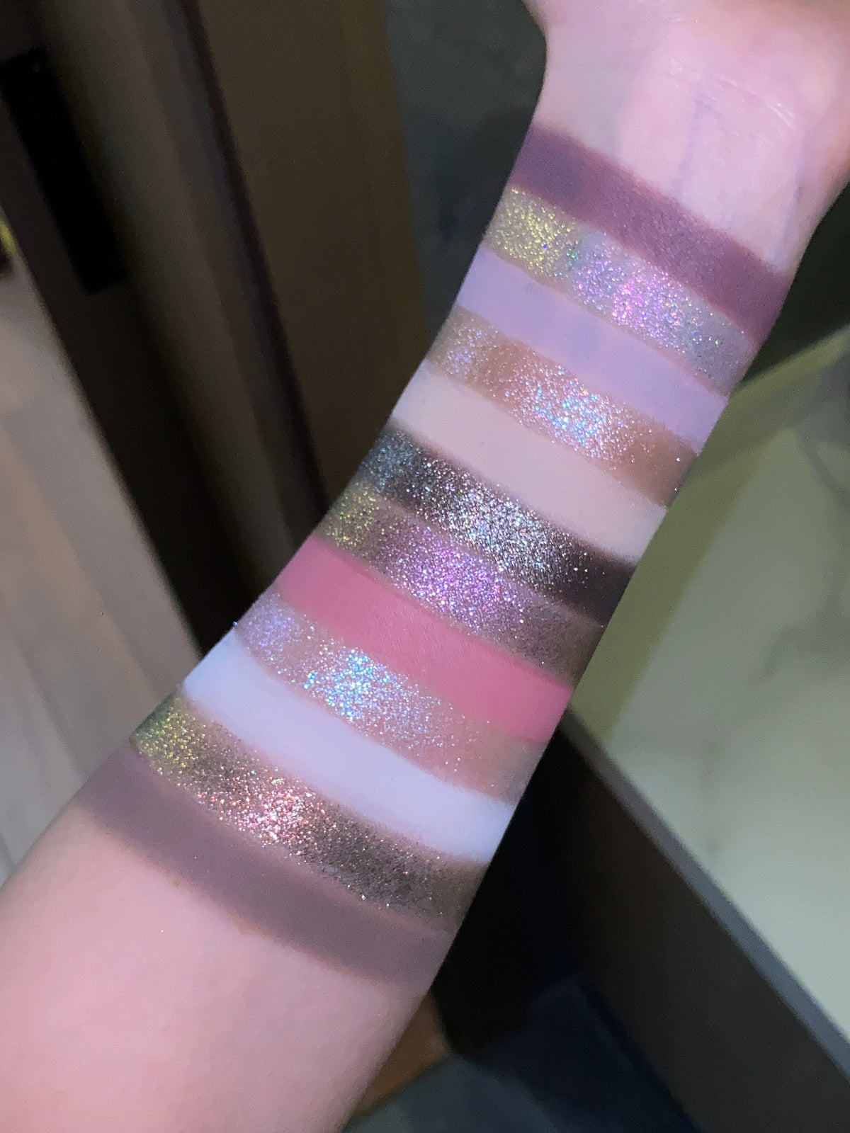 Pâtisserie arm swatches in indoor light, rose and plum mattes between multicoloured sparkle shades